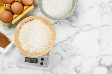 Photo of Flat lay composition of kitchen scale with bowl of flour and products on white marble table. Space for text