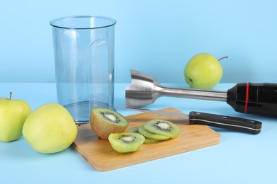 Photo of Hand blender kit, fresh fruits and knife on light blue background