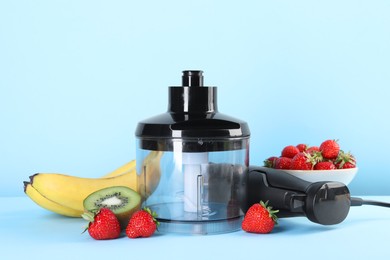 Photo of Hand blender kit, fresh fruits and strawberries on light blue background