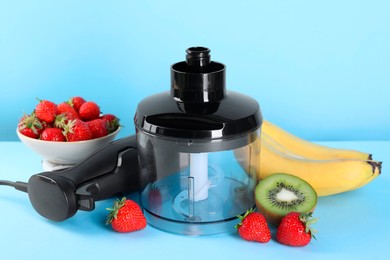 Hand blender kit, fresh fruits and strawberries on light blue background