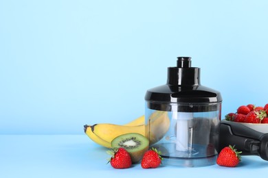 Photo of Hand blender kit, fresh fruits and strawberries on light blue background, space for text