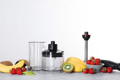 Photo of Hand blender kit, fresh fruits and strawberries on gray table against white background