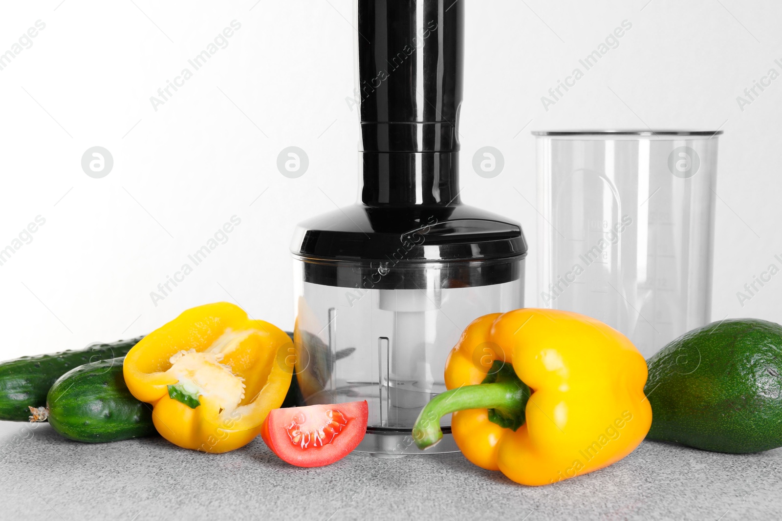 Photo of Hand blender kit and fresh vegetables on gray table against white background