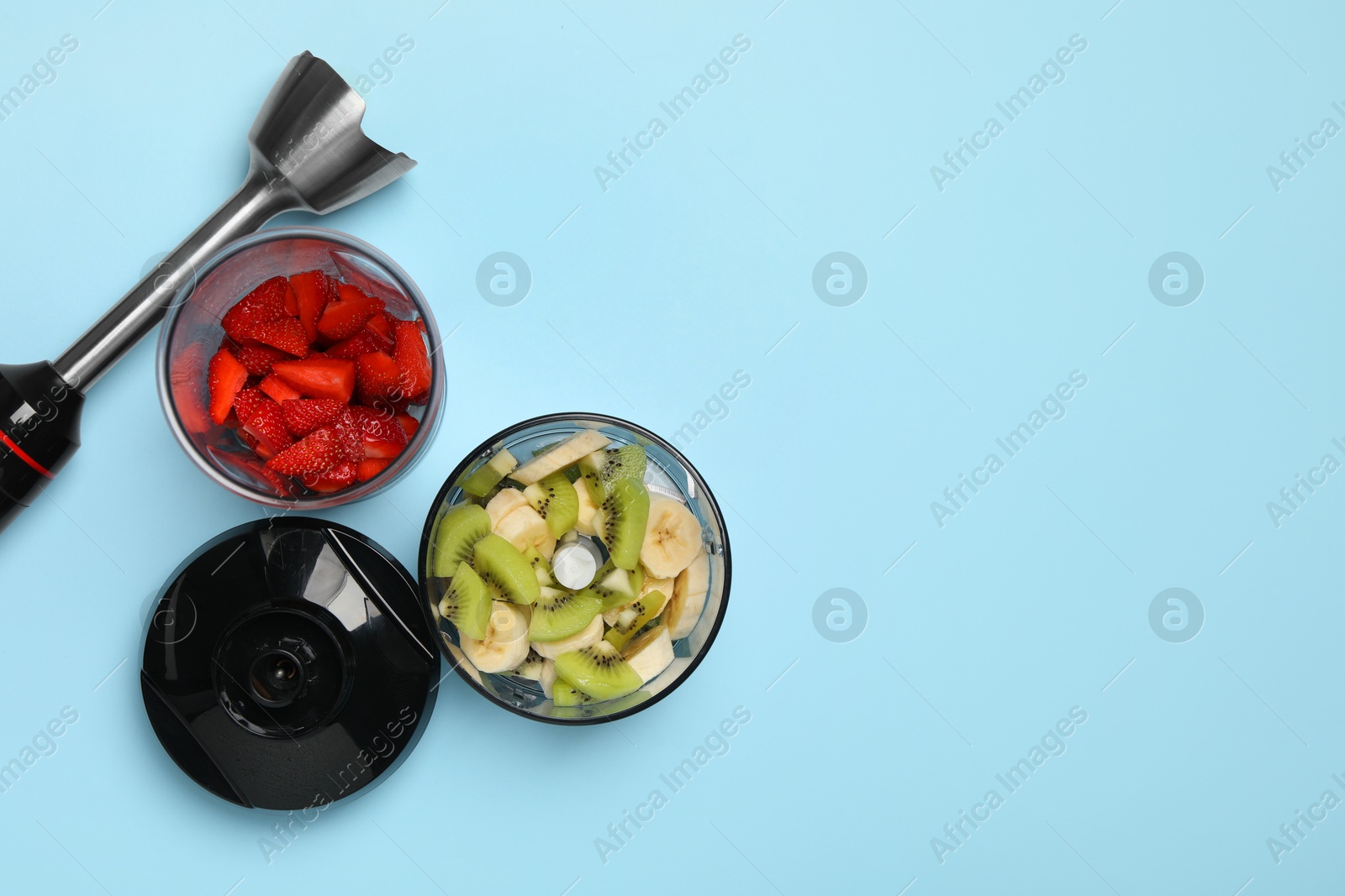 Photo of Hand blender kit, fresh fruits and strawberries on light blue background, flat lay. Space for text