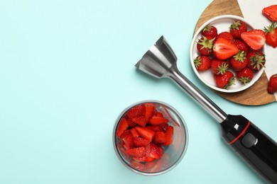 Photo of Hand blender kit and fresh strawberries on turquoise background, flat lay. Space for text