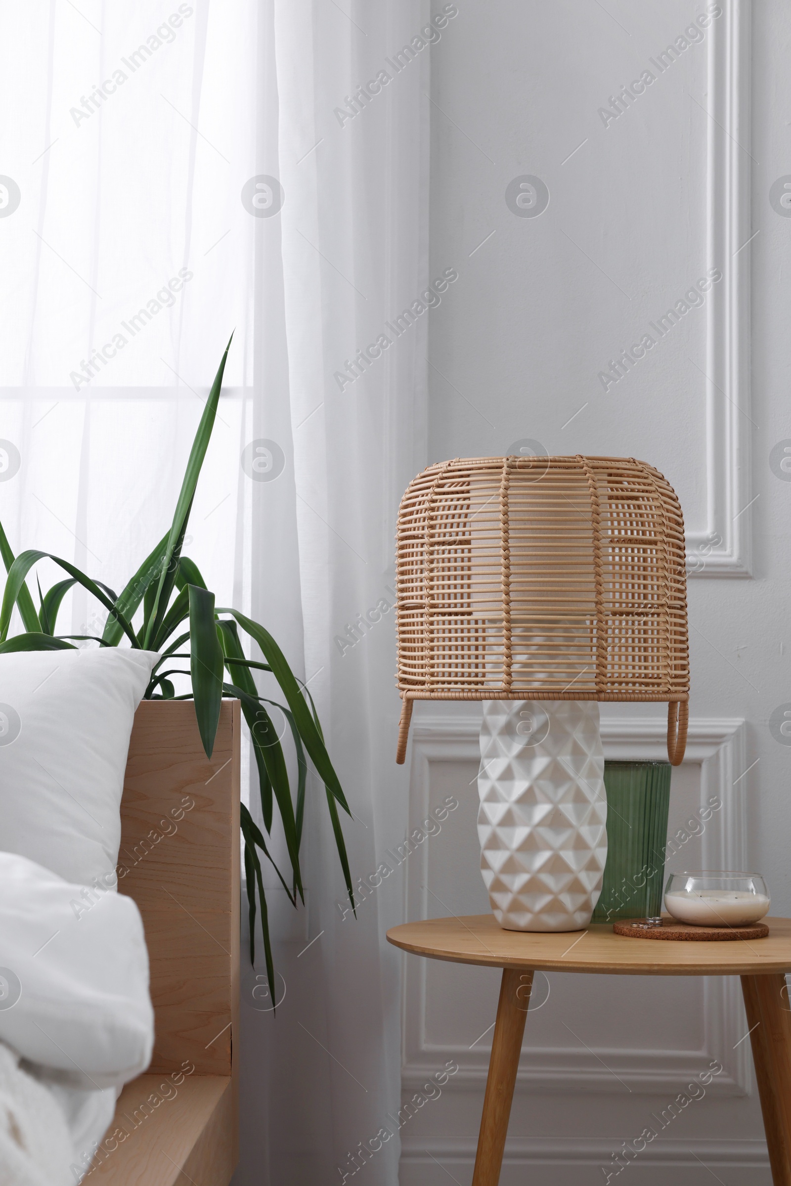 Photo of Stylish living room interior with bed, bedside table, lamp and houseplants