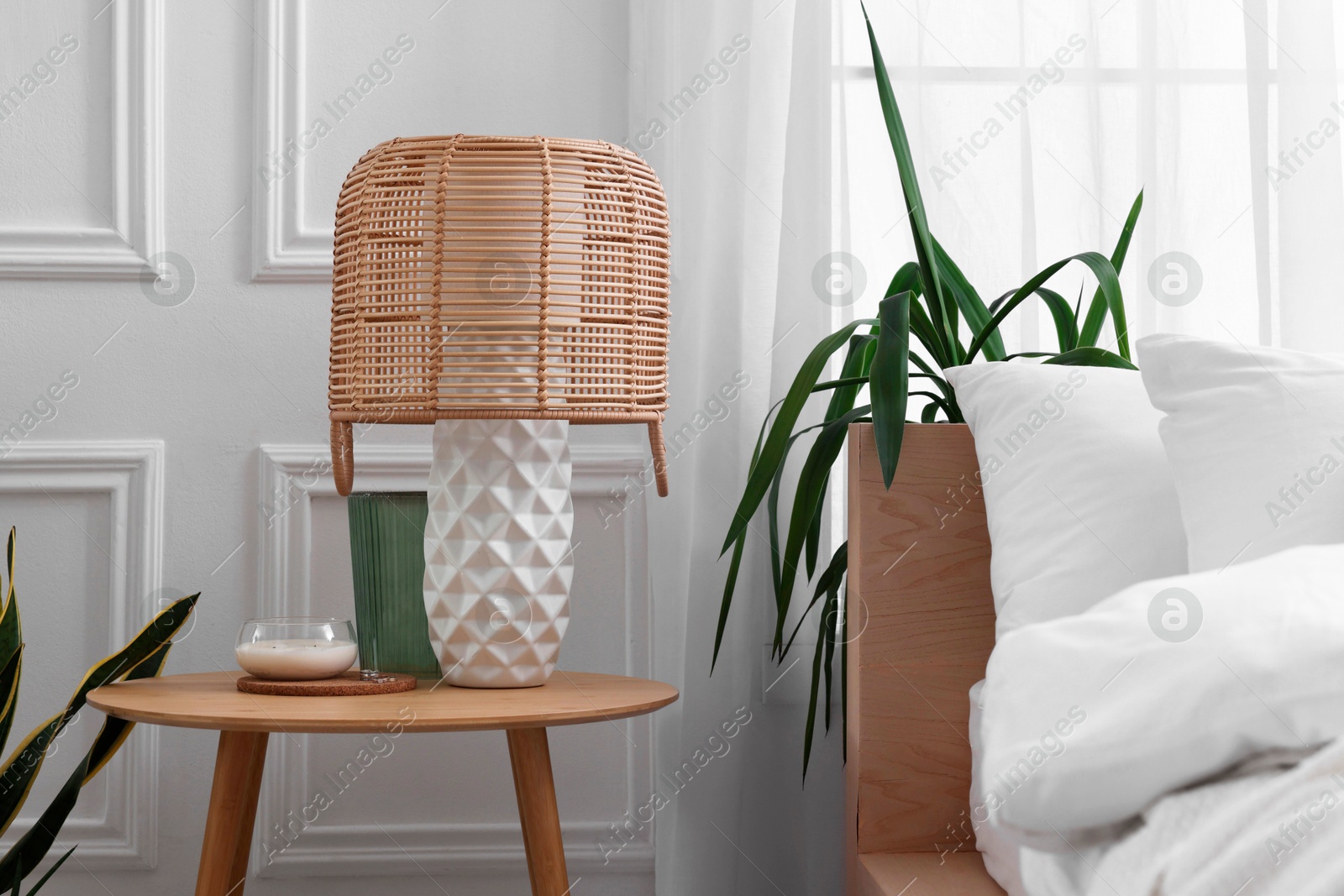 Photo of Stylish living room interior with bed, bedside table, lamp and houseplants