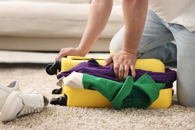 Man packing suitcase on floor at home, closeup