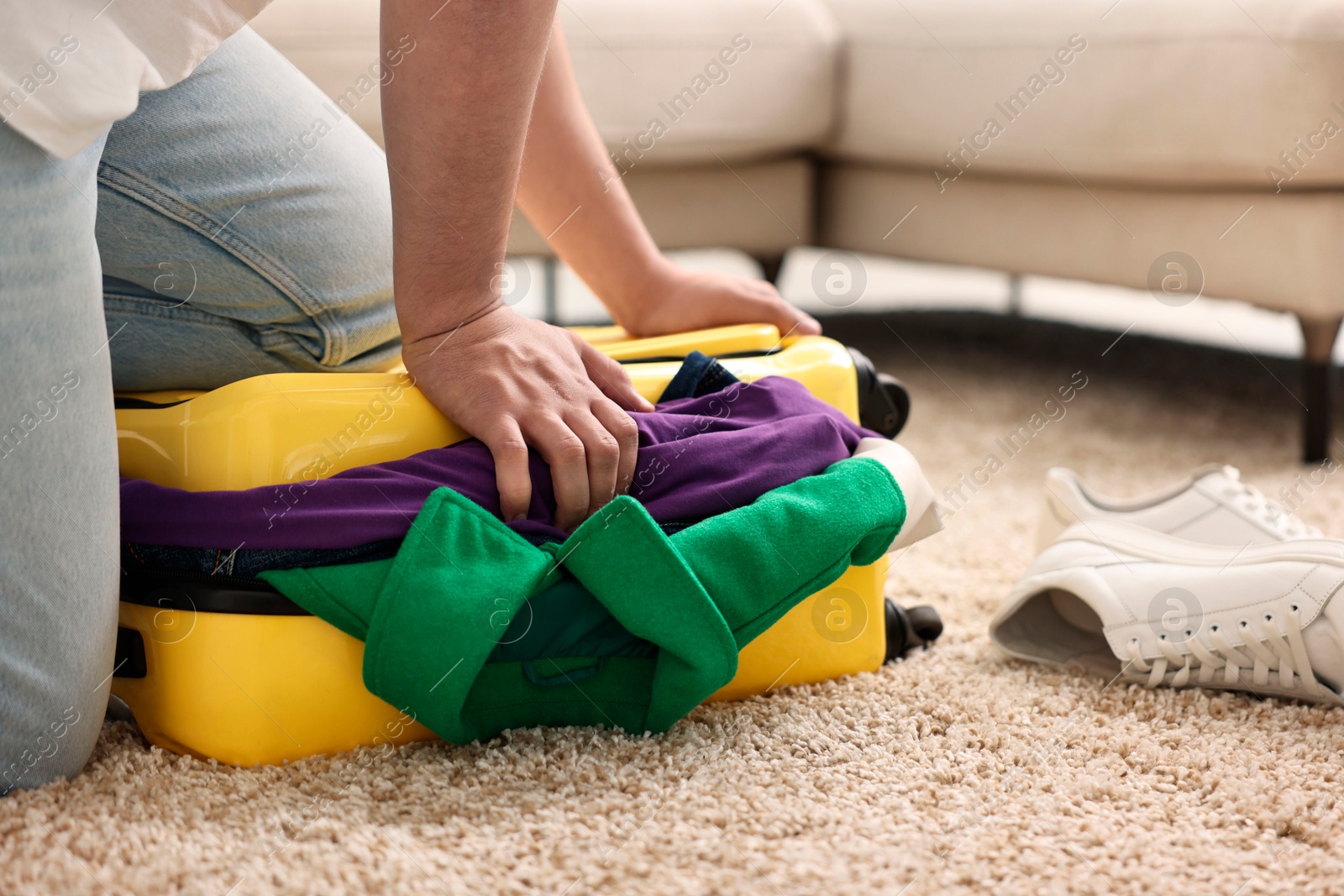 Photo of Man packing suitcase on floor at home, closeup