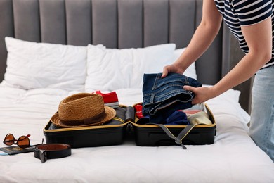 Photo of Man packing suitcase for trip in bedroom, closeup