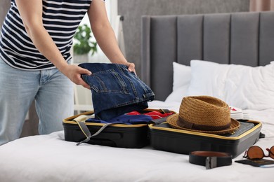 Photo of Man packing suitcase for trip in bedroom, closeup