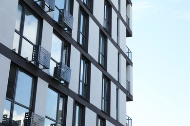 Photo of Modern building with big windows against blue sky outdoors, space for text