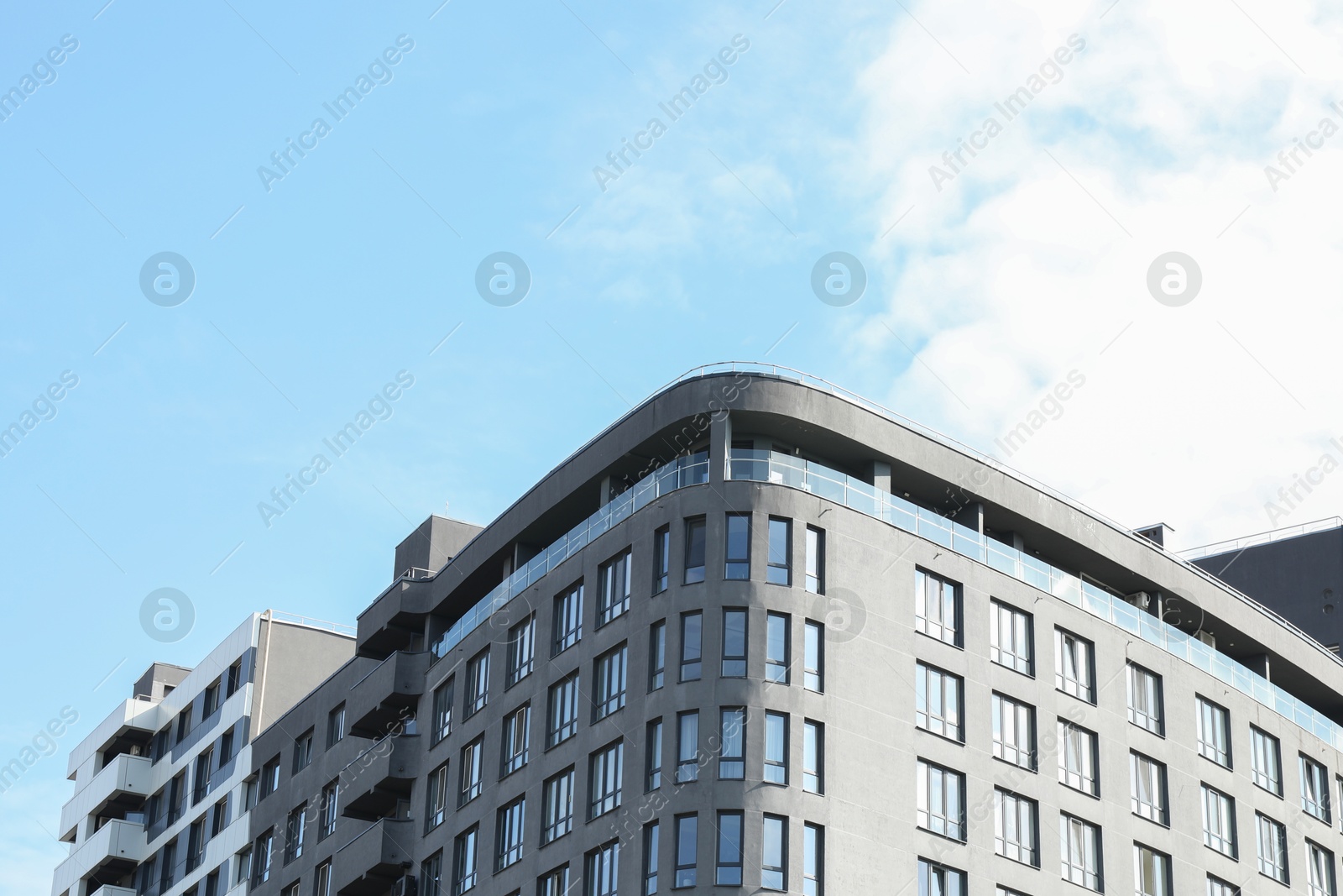 Photo of Modern building with big windows against blue sky outdoors, space for text