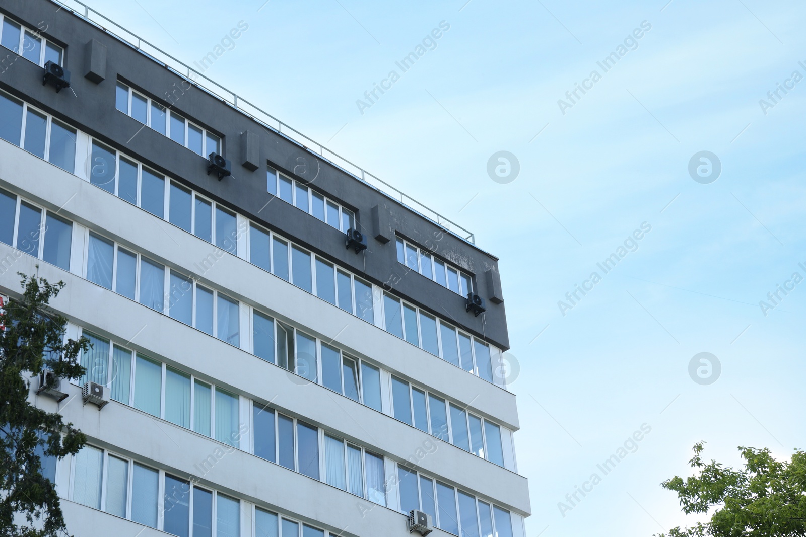 Photo of Modern building with big windows outdoors, low angle view. Space for text