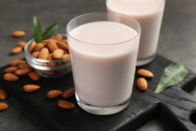 Photo of Glasses of almond milk and almonds on grey table