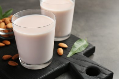 Photo of Glasses of almond milk and almonds on grey table, space for text