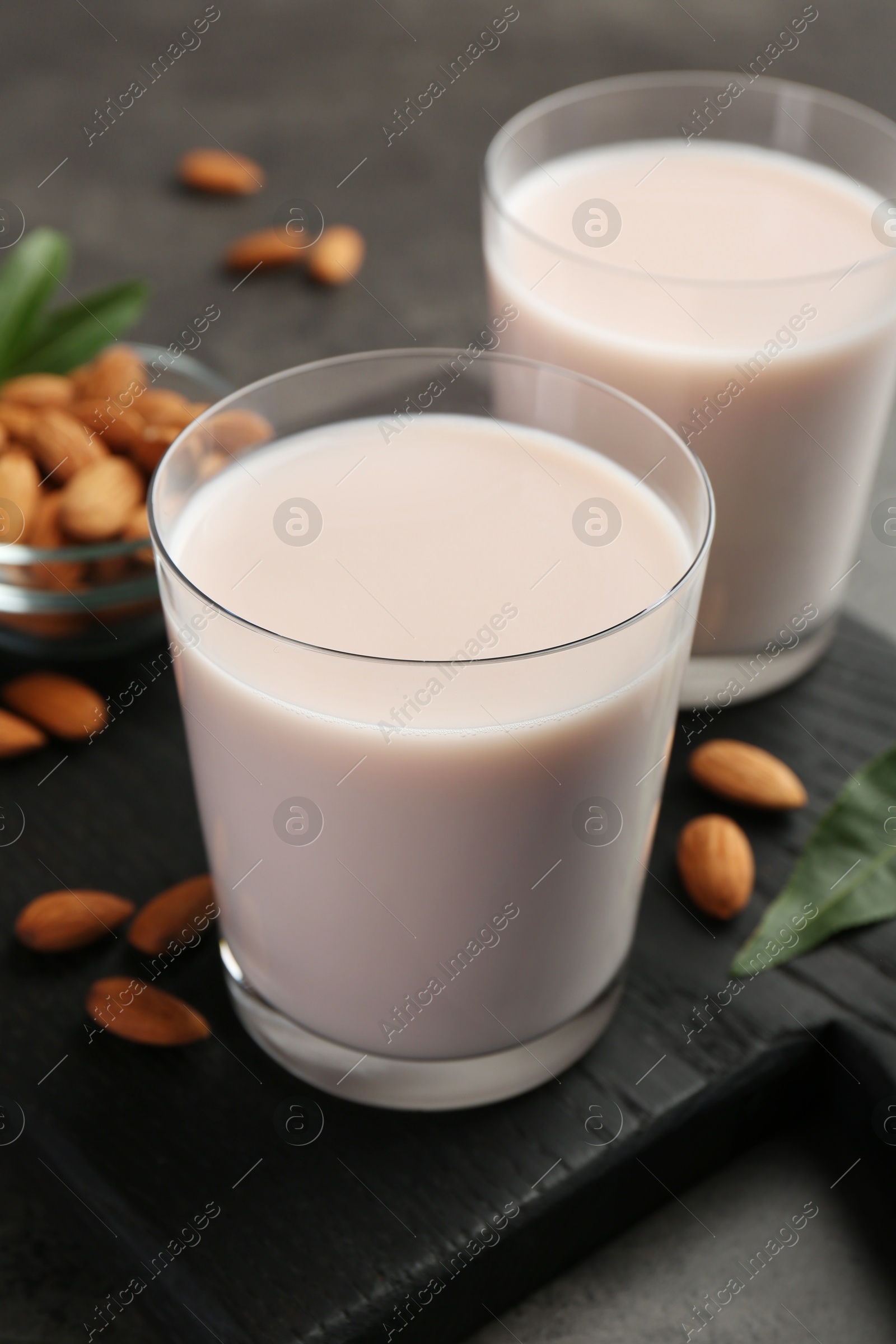 Photo of Glasses of almond milk and almonds on grey table