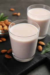 Photo of Glasses of almond milk and almonds on grey table