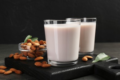 Photo of Glasses of almond milk and almonds on grey table