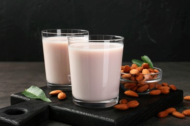 Photo of Glasses of almond milk and almonds on grey table