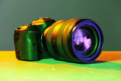 Modern photo camera in neon lights on table