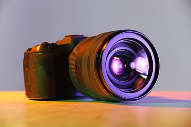 Photo of Modern photo camera in neon lights on table