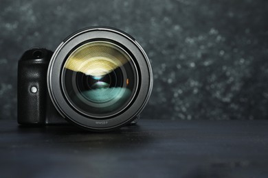 Photo of Modern photo camera on black table, space for text