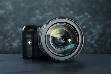 Modern photo camera on black table. Photographer's equipment