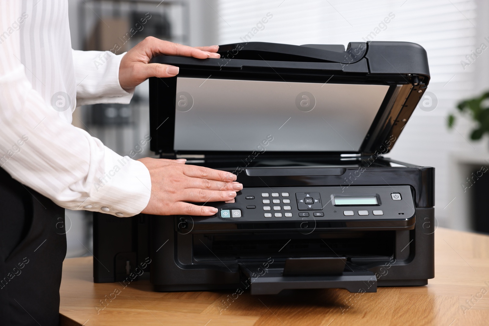 Photo of Woman using modern printer at workplace indoors, closeup