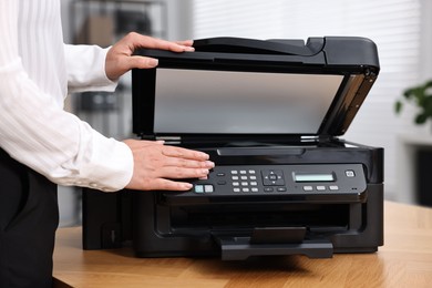 Photo of Woman using modern printer at workplace indoors, closeup