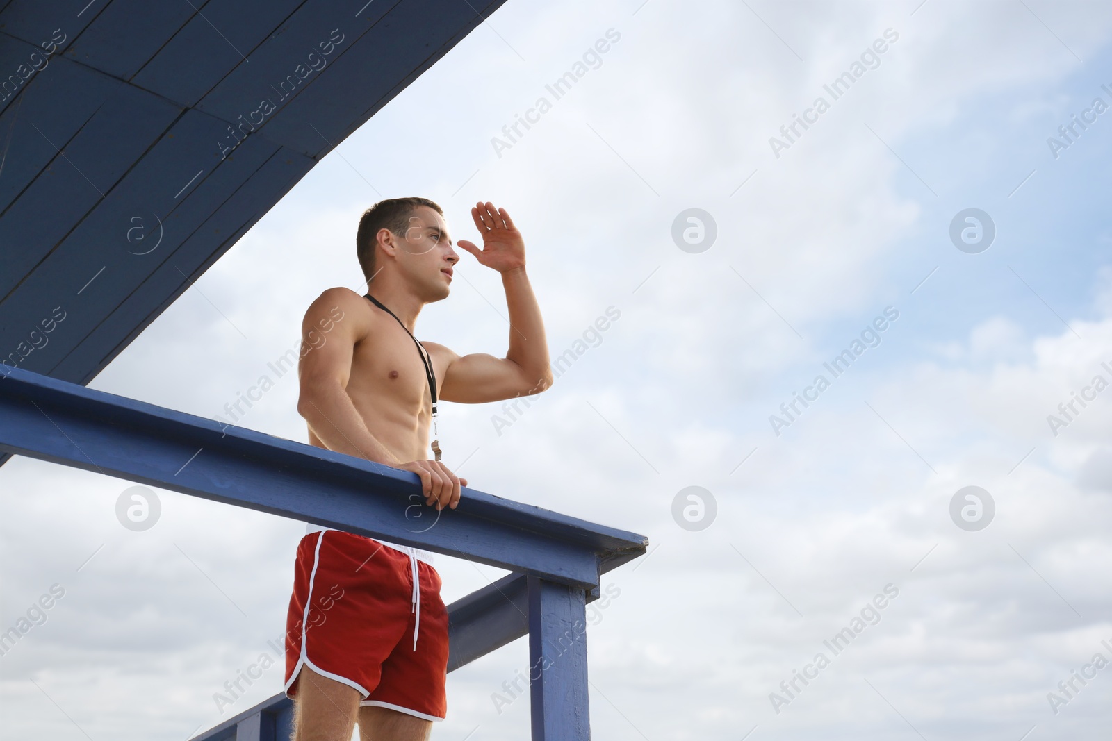 Photo of Handsome lifeguard on watch tower against sky