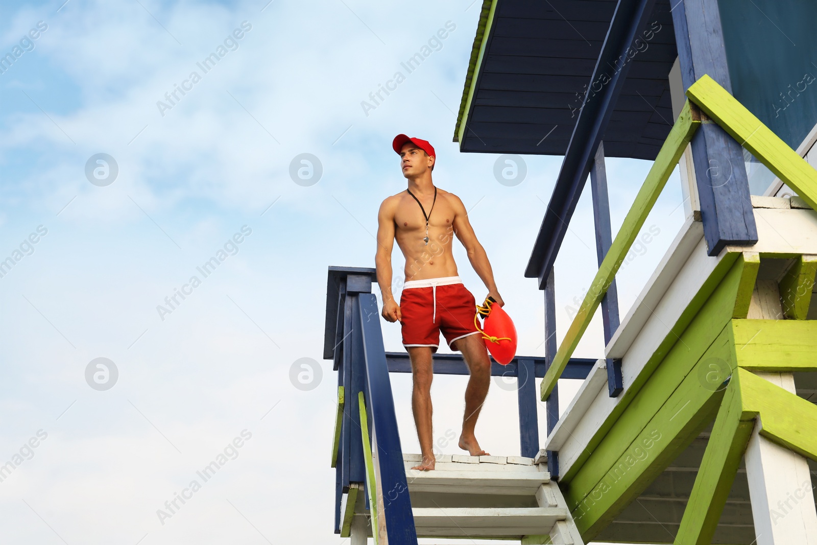 Photo of Handsome lifeguard with life buoy on watch tower