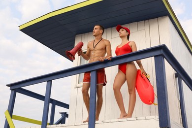 Photo of Professional lifeguards with life buoy and megaphone on watch tower