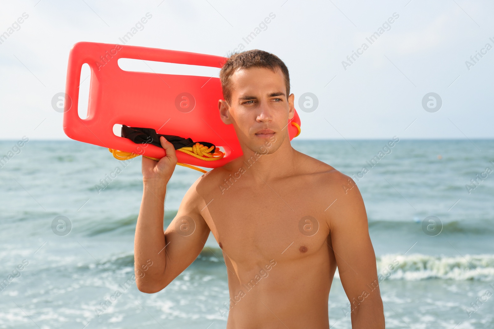 Photo of Handsome lifeguard with life buoy near sea