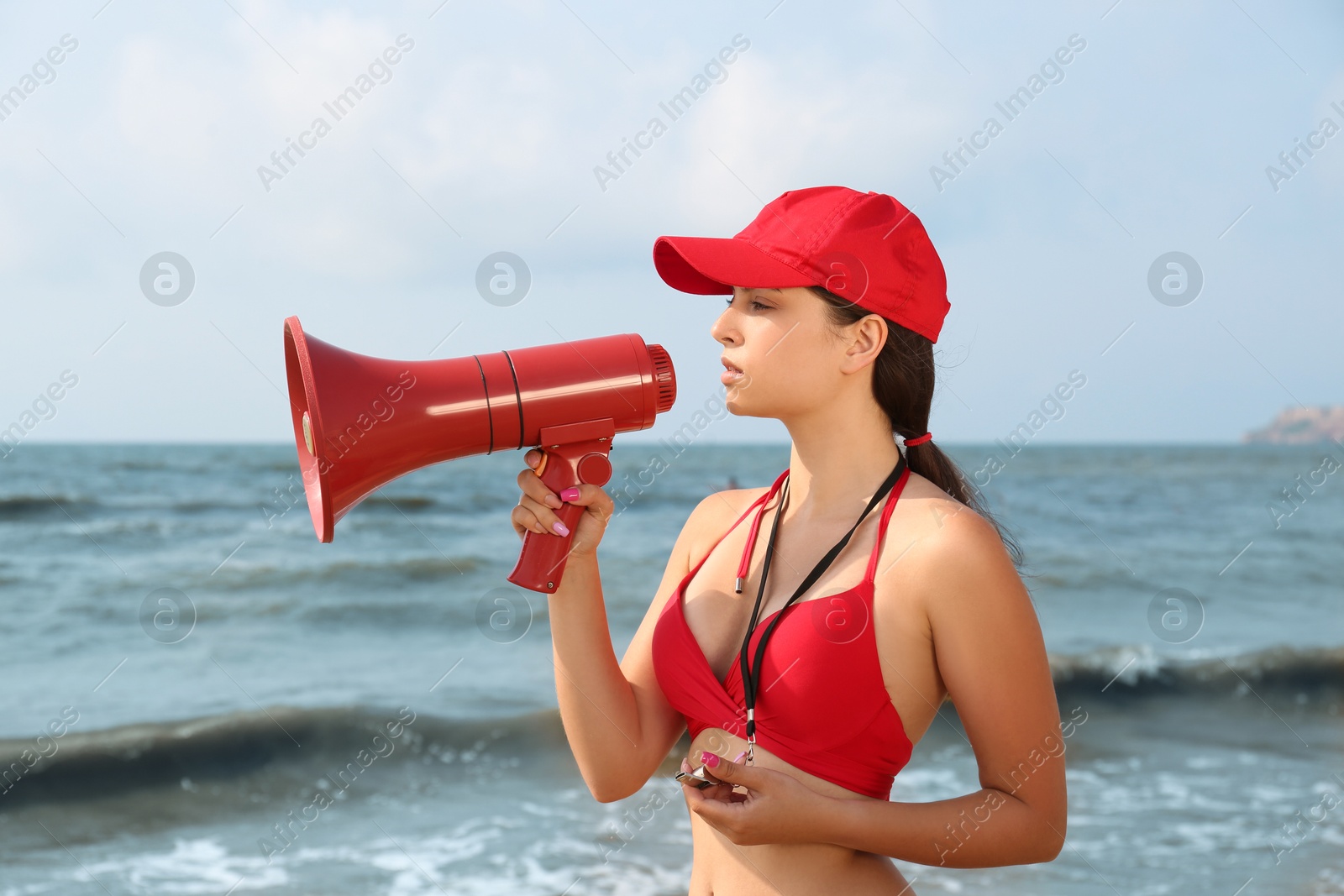 Photo of Beautiful young lifeguard with megaphone near sea