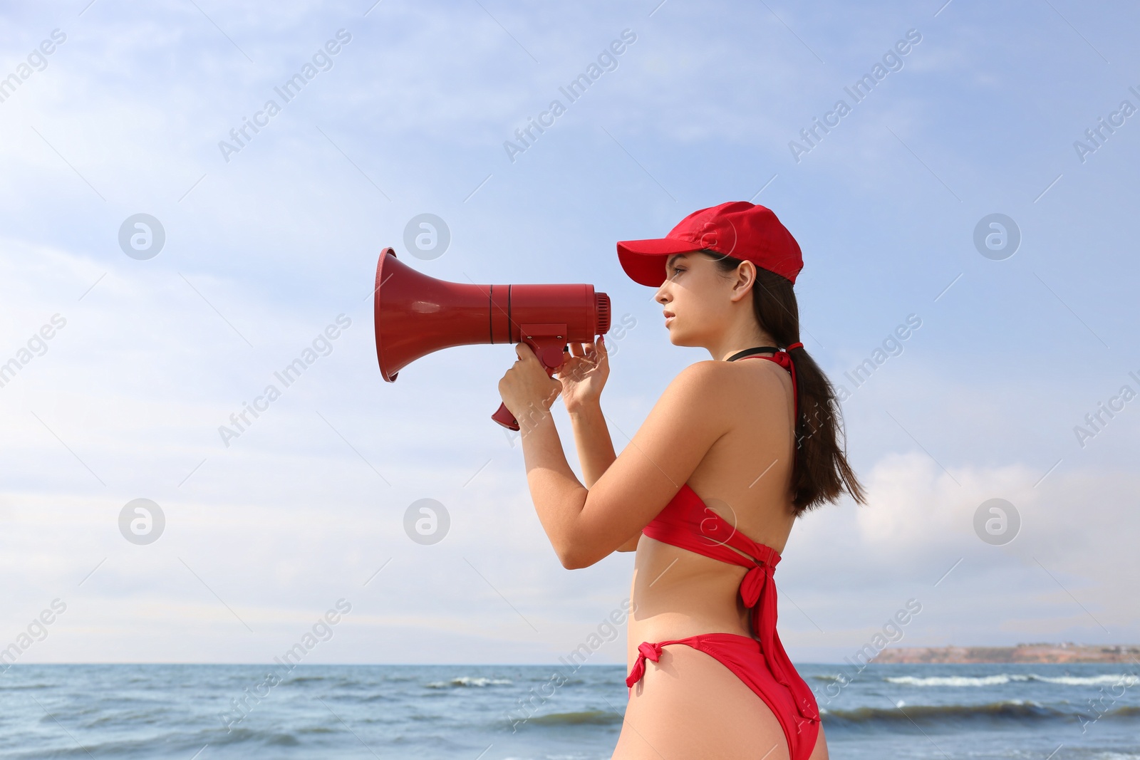 Photo of Beautiful young lifeguard with megaphone near sea