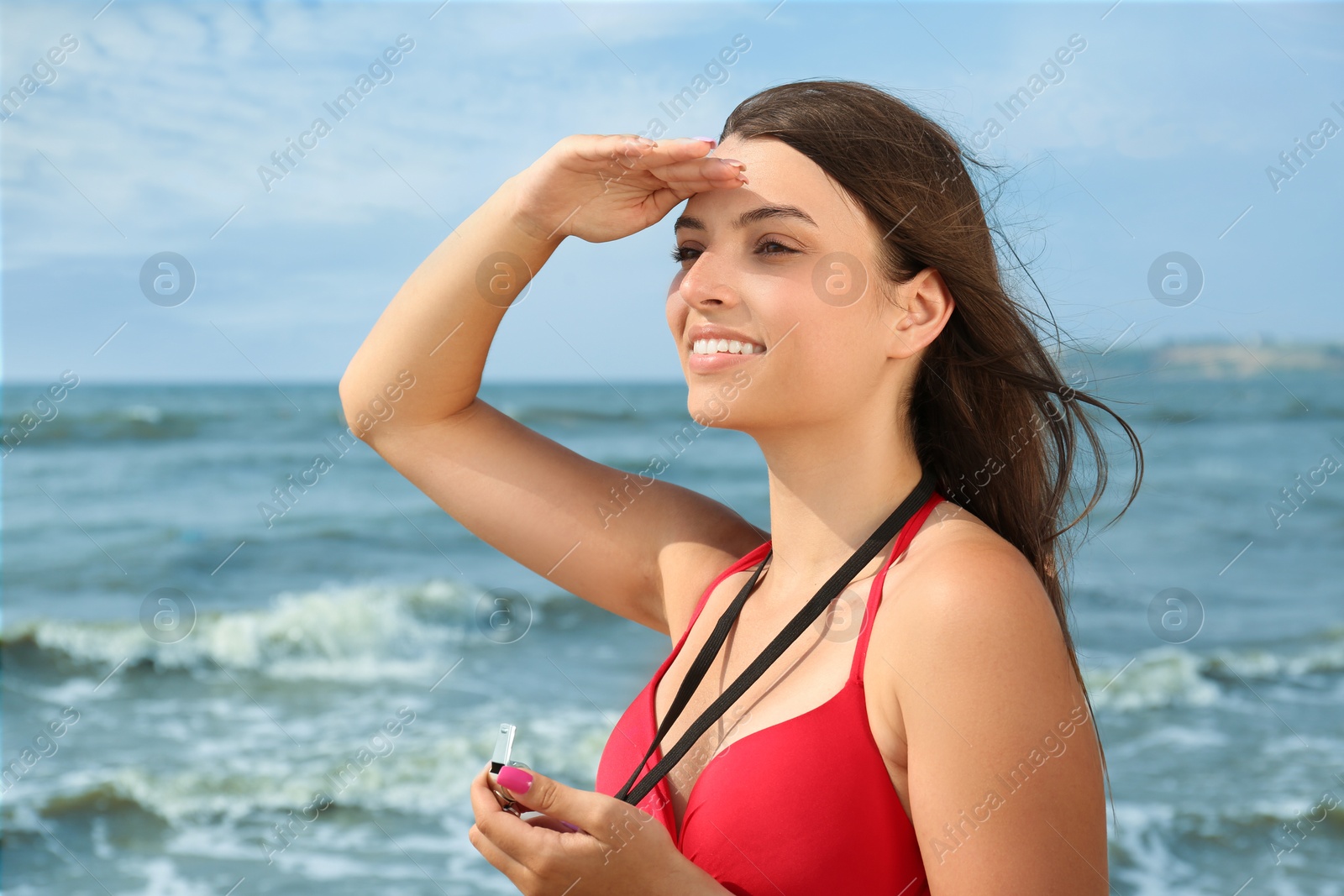 Photo of Beautiful young lifeguard with whistle near sea