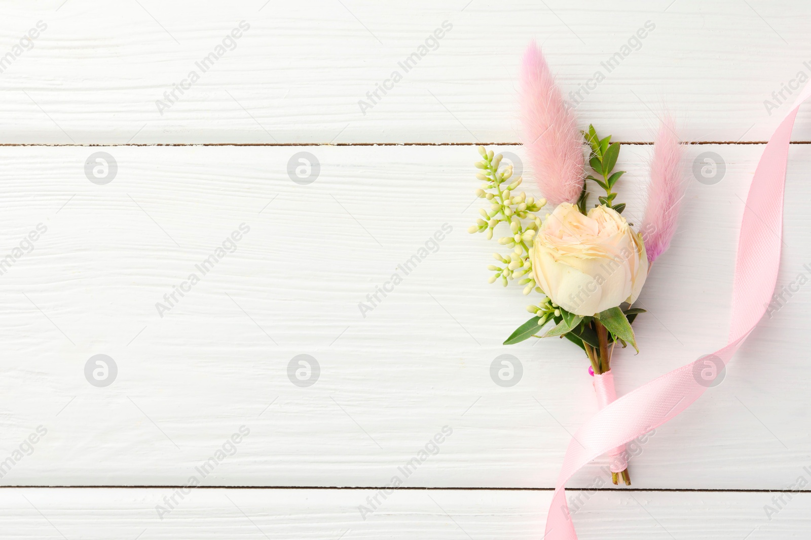 Photo of Small stylish boutonniere and ribbon on white wooden table, top view. Space for text