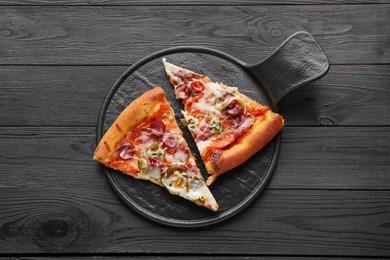 Photo of Board with pieces of delicious pizza Diablo on black wooden table, top view