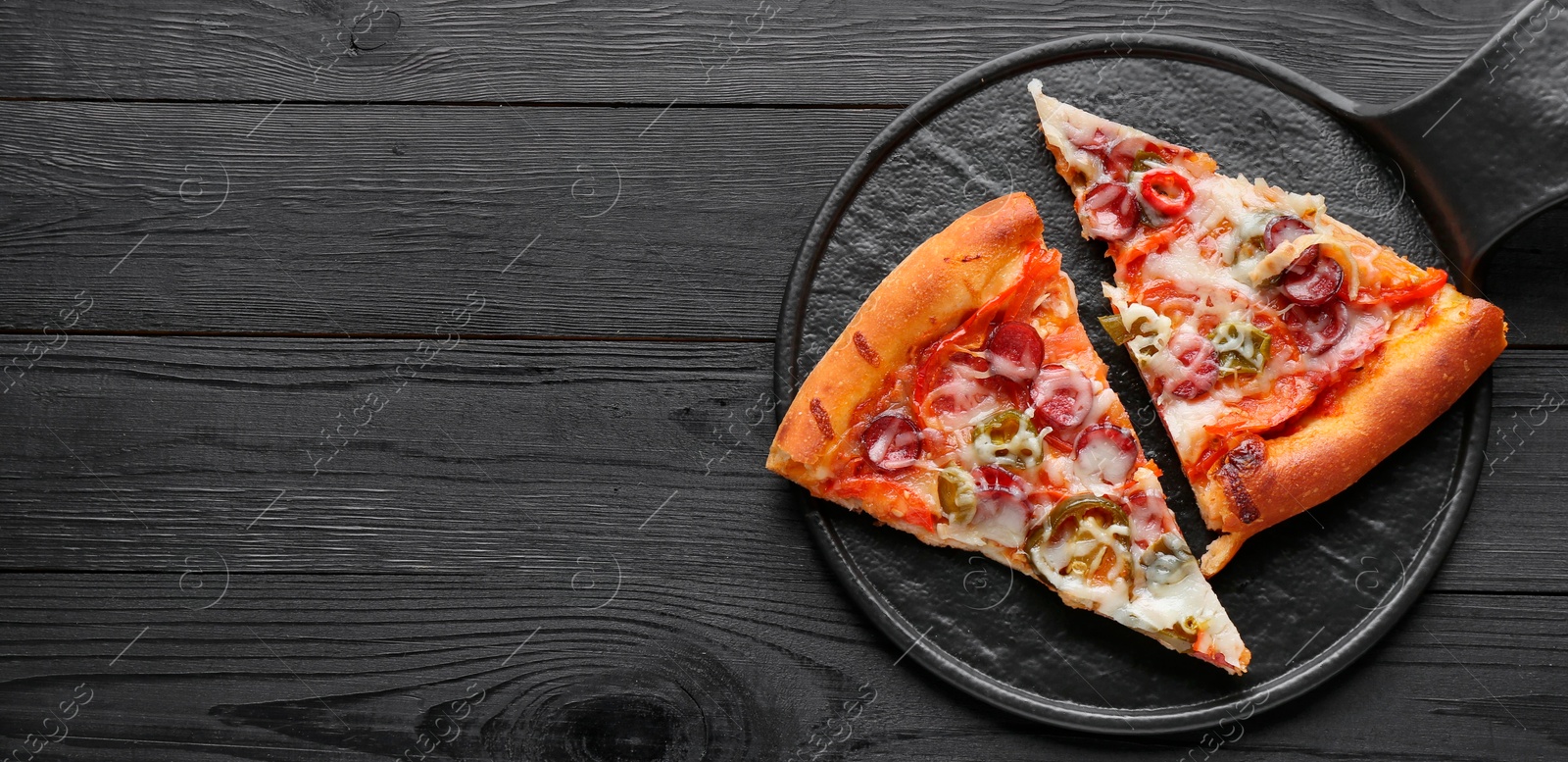 Photo of Board with pieces of delicious pizza Diablo on black wooden table, top view. Space for text