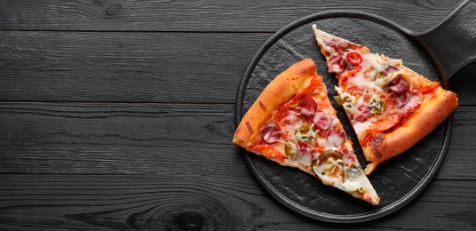 Board with pieces of delicious pizza Diablo on black wooden table, top view. Space for text