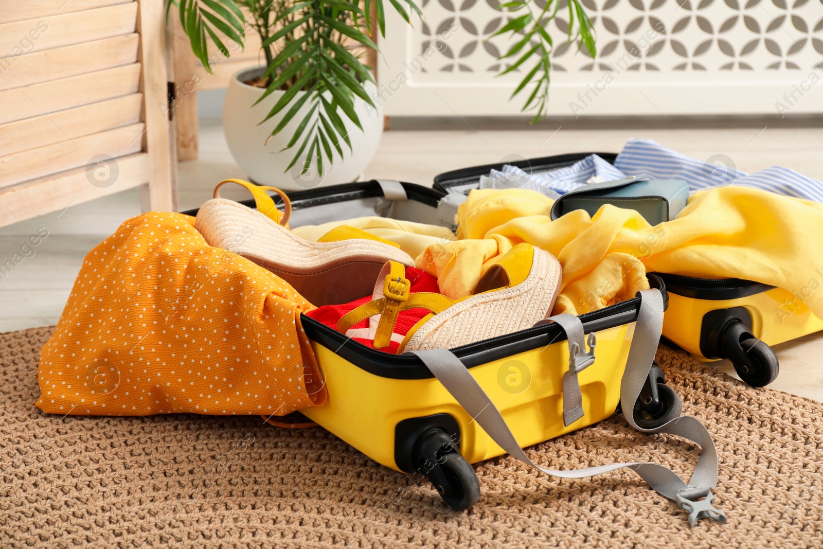 Photo of Open suitcase with traveler's belongings on floor indoors