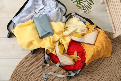 Open suitcase with traveler's belongings on floor, top view