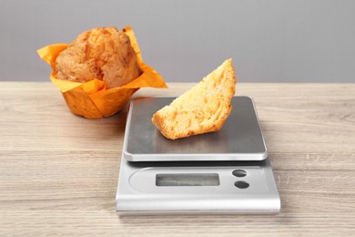 Photo of Kitchen scale with piece of muffin on light wooden table