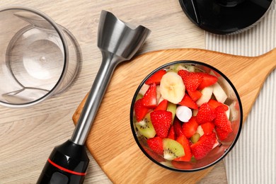 Hand blender kit with fresh fruits and strawberries on wooden table, flat lay