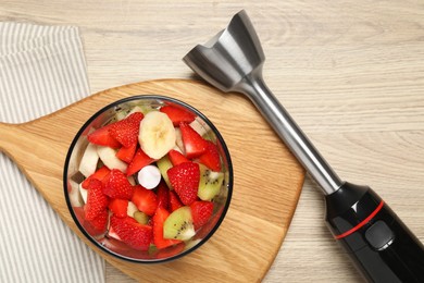 Hand blender kit with fresh fruits and strawberries on wooden table, flat lay