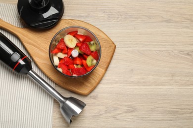 Hand blender kit with fresh fruits and strawberries on wooden table, flat lay. Space for text