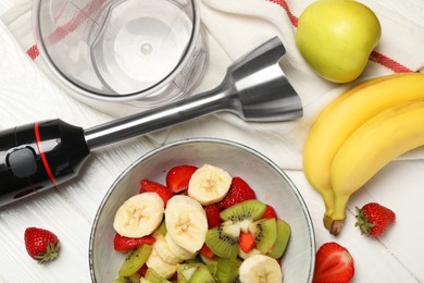 Photo of Hand blender kit, fresh fruits and strawberries in bowl on white wooden table, flat lay