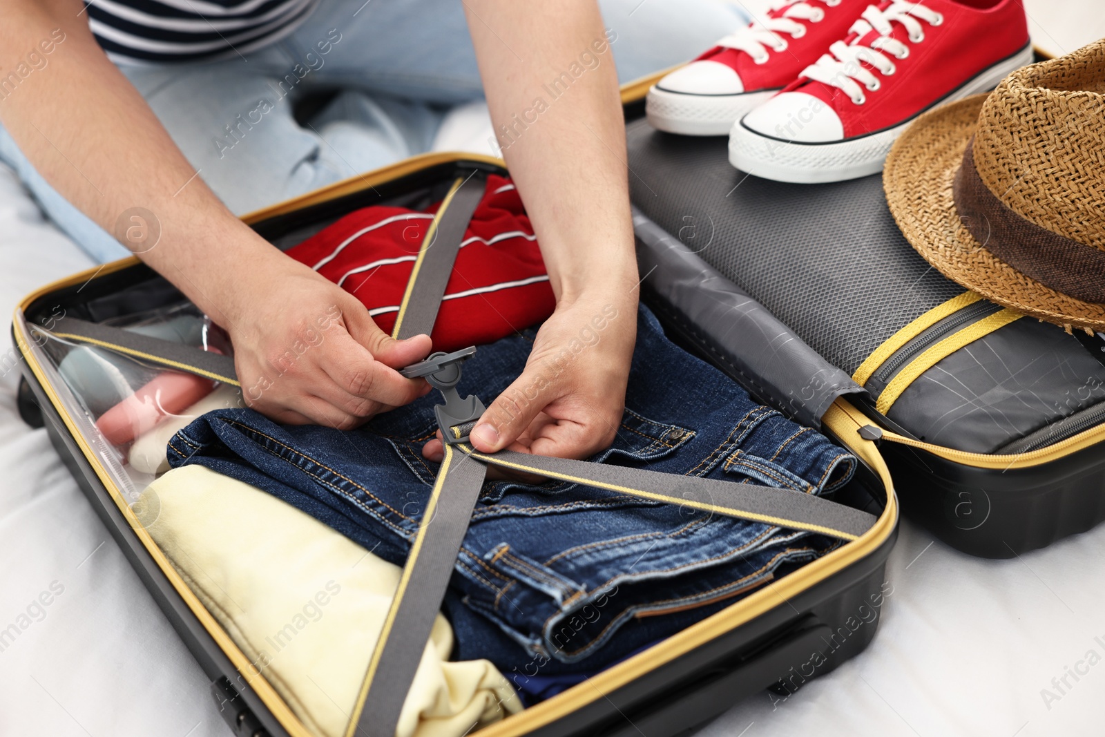 Photo of Man packing suitcase for trip on bed, closeup