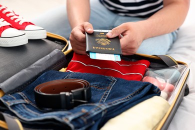 Man packing suitcase for trip on bed, closeup